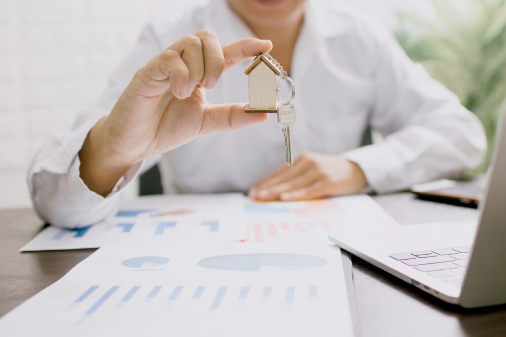 Person sitting at desk holding a keychain shaped like a house