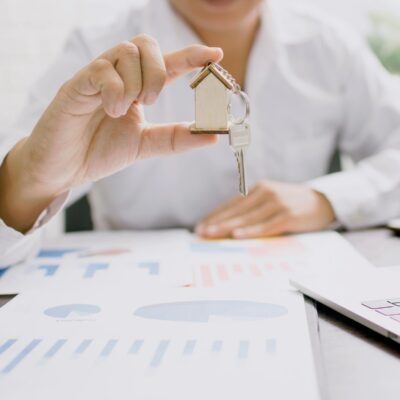 Person sitting at desk holding a keychain shaped like a house